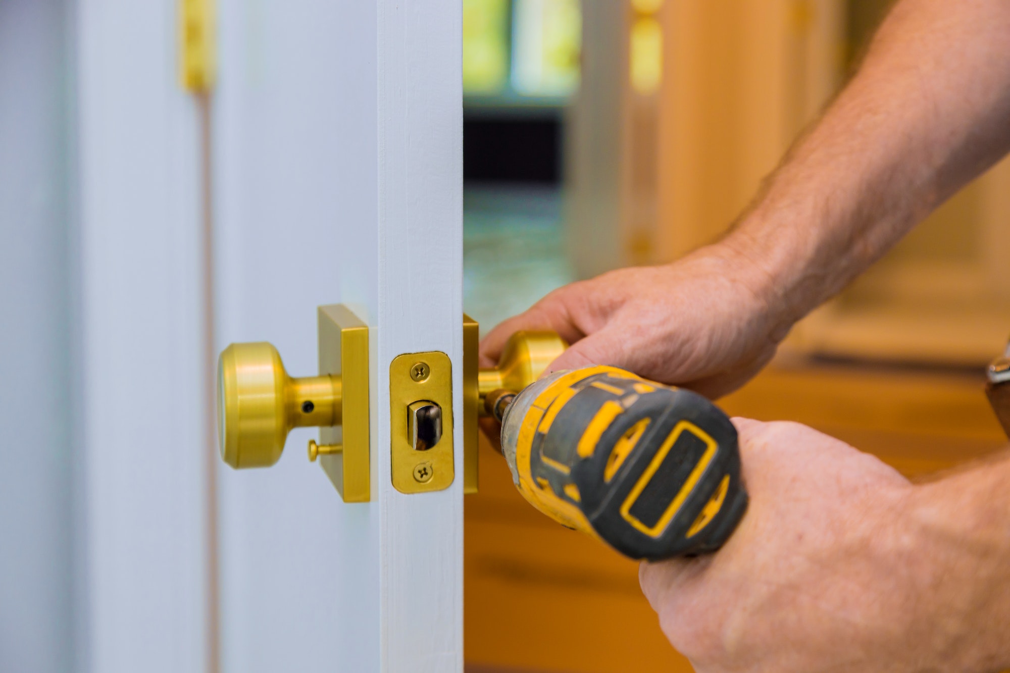 Closeup of a professional locksmith installing or new lock on a house door handle with screwdriver