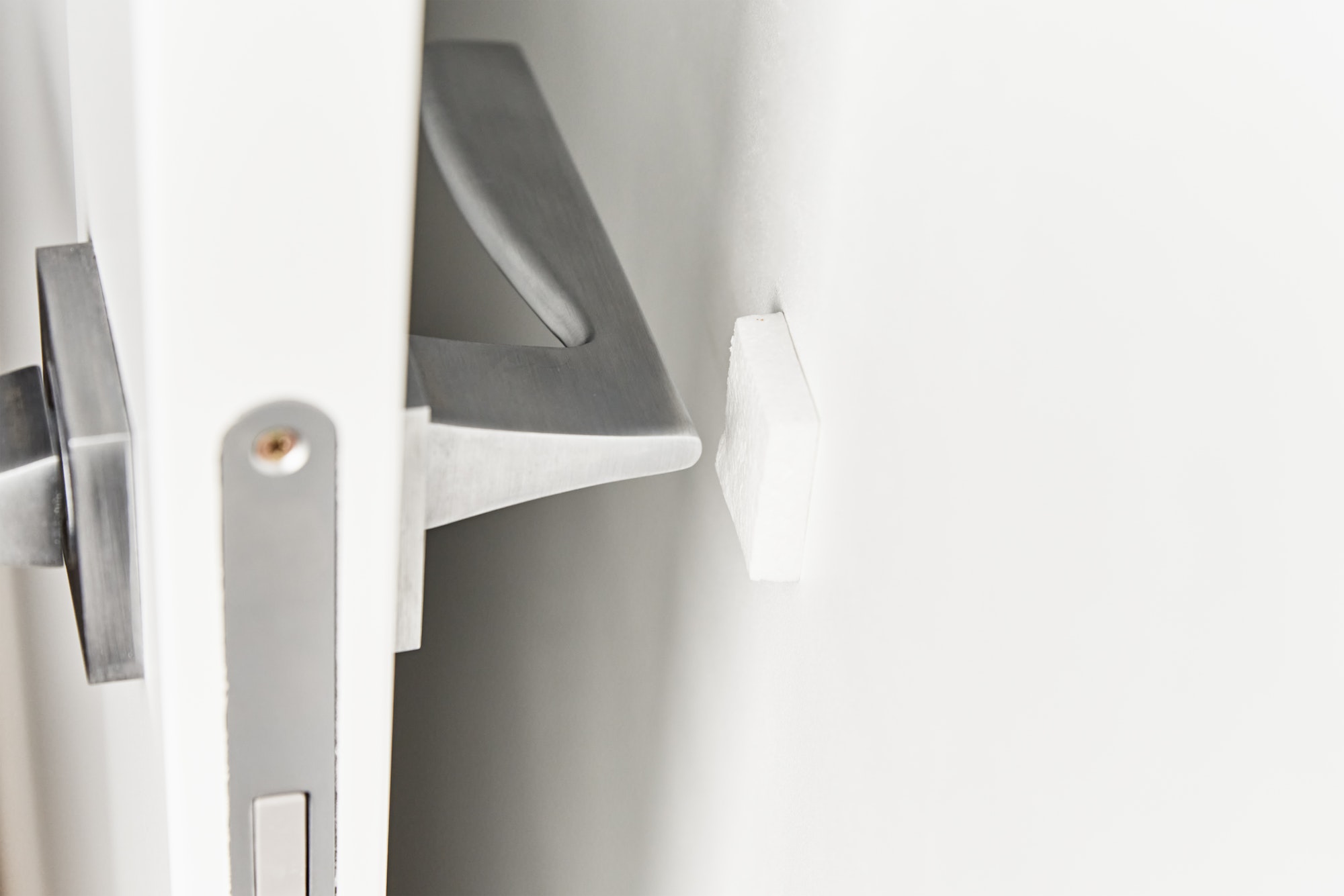 Silver door handle on a white door. Furniture accesories, interior element